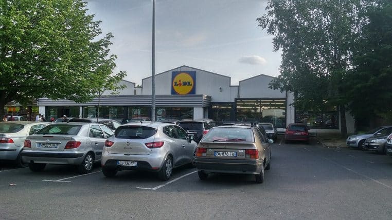 Façade d’un supermarché Lidl à Paris, logo bien visible, voitures garées devant l’entrée, ciel couvert.