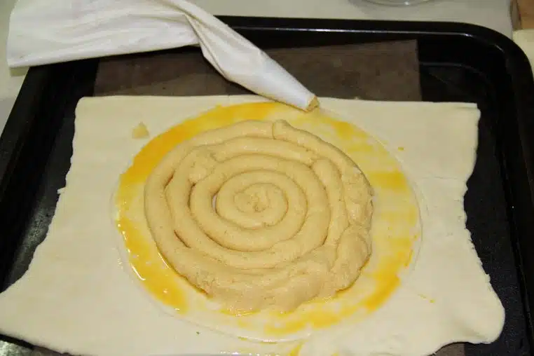 Préparation d’une galette des rois sur plan de travail, pâte feuilletée et garniture avant cuisson, étape de montage en cuisine.
