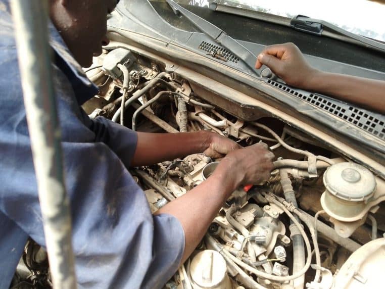 Un mécanicien répare un moteur dans le compartiment moteur, mains au travail, gros plan sur la mécanique