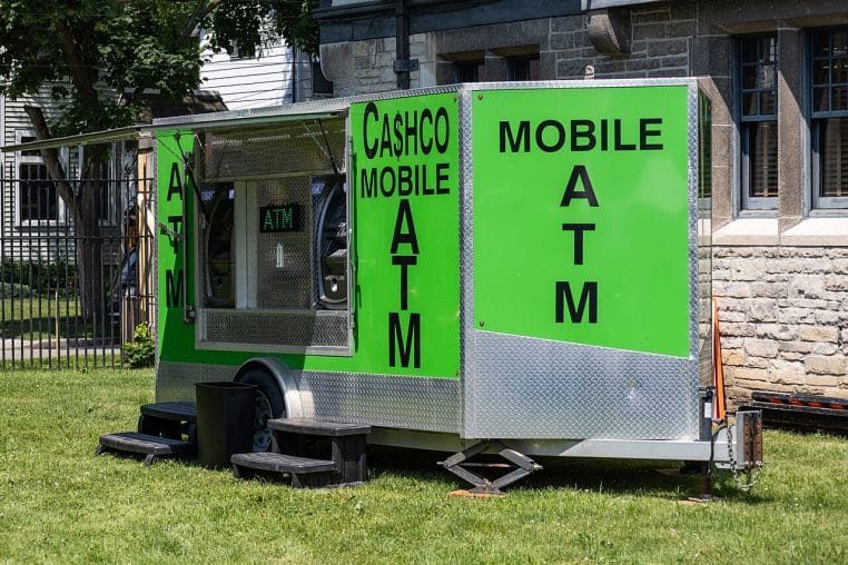 Un distributeur automatique mobile stationné en extérieur, véhicule équipé d’un ATM et signalétique visible sur le côté