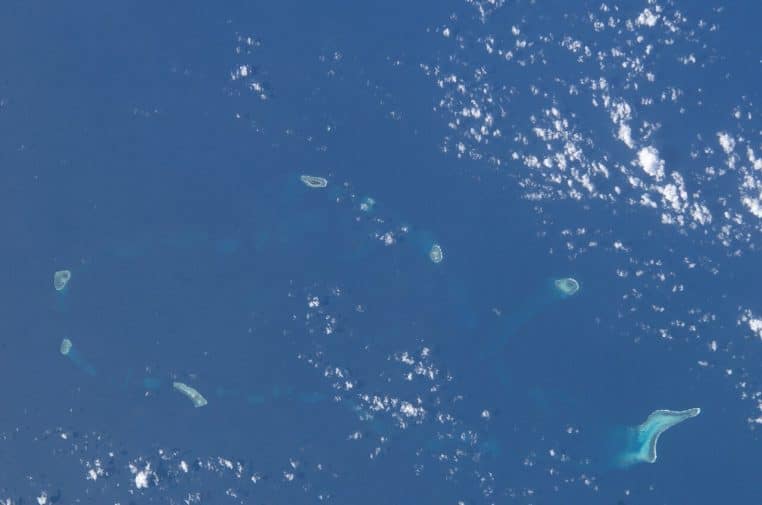 Photo ISS de la mer de Chine méridionale montrant plusieurs récifs et îlots dispersés sous des nuages.