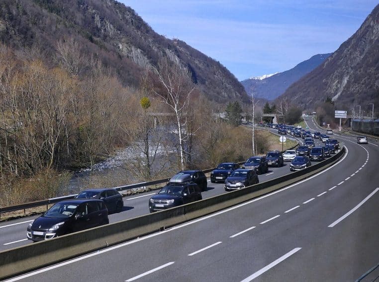 Long embouteillage sur une route de montagne en hiver, files de voitures à l’arrêt dans la neige vers des stations alpines.