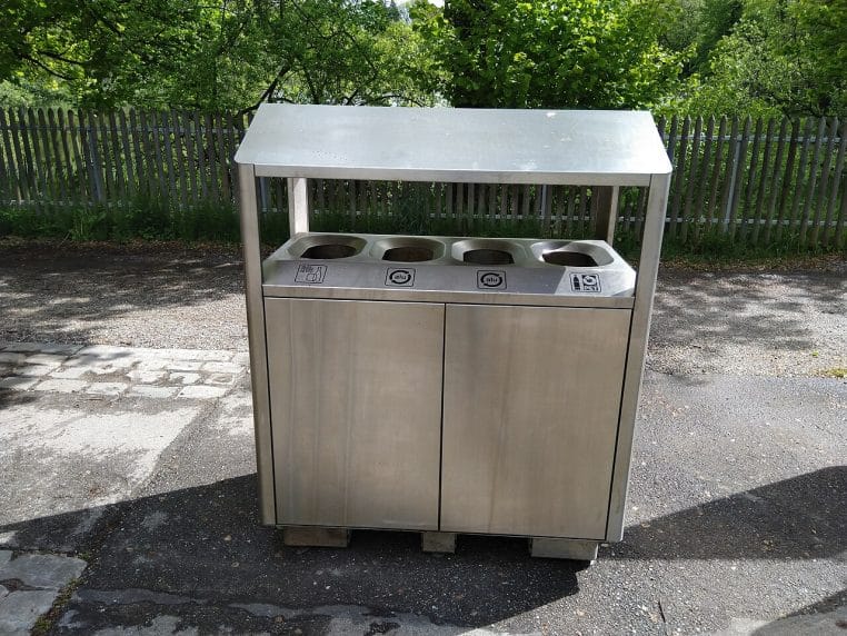 Point de collecte avec bacs de tri pour verre, canettes et bouteilles, en extérieur, en journée