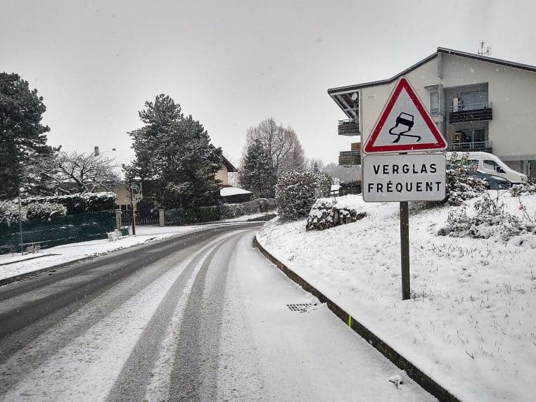 Route enneigée avec panneau « verglas fréquent », circulation délicate et paysage d’hiver en Haute-Savoie.
