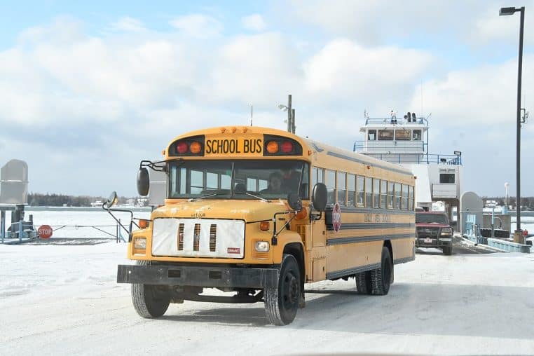 Bus scolaire sur une chaussée enneigée en pleine lumière d’hiver, arrière-plan de transport et quai