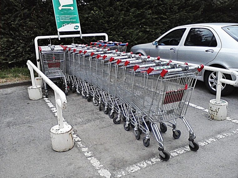 Route d’une zone commerciale en périphérie, bordée d’enseignes et de parkings, un dimanche calme.