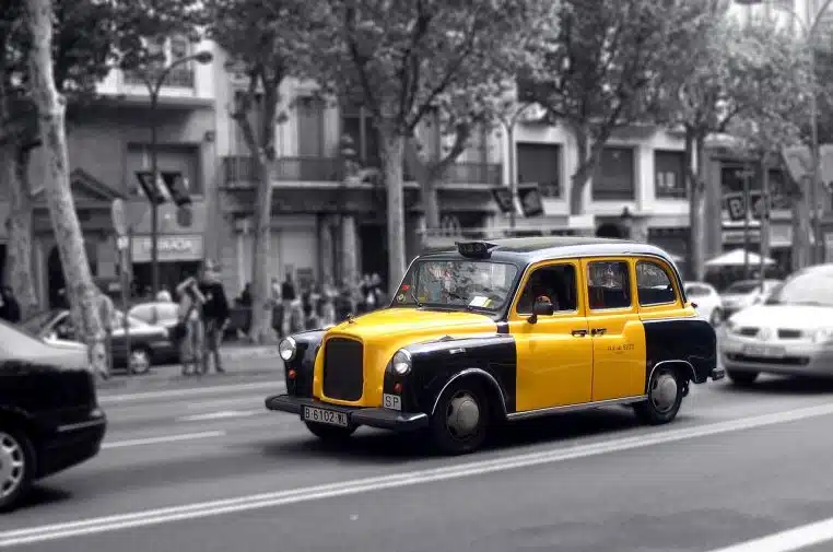 Taxi noir et jaune à Barcelone roulant en pleine rue, image horizontale idéale pour illustrer le sujet.