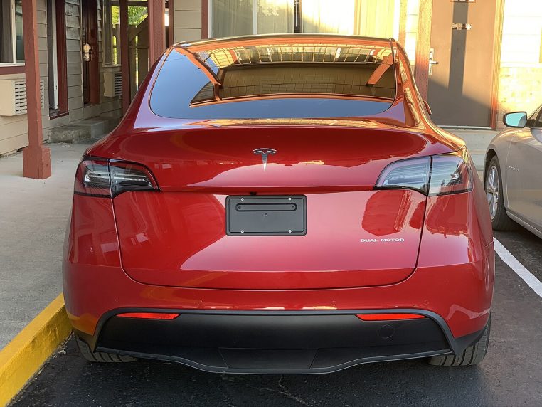 Vue arrière d’un Tesla Model Y stationné de nuit, feux visibles sur le hayon.