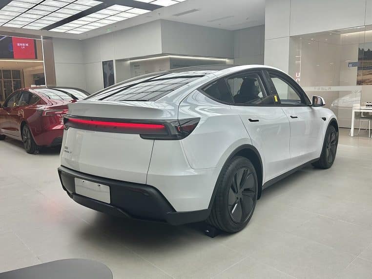 Tesla Model Y photographié de trois-quarts, stationné en extérieur, détails de la face avant et des jantes visibles.