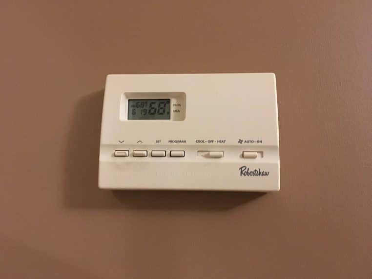 Thermostat mural affichant une consigne de température, fixé sur un mur intérieur de logement.