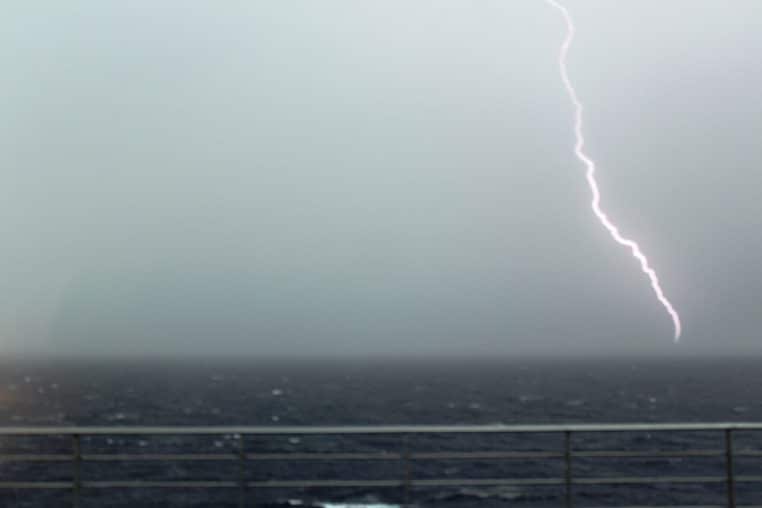 Éclair tombant sur la mer au loin, horizon sombre et vents forts, scène d’orage sur le littoral