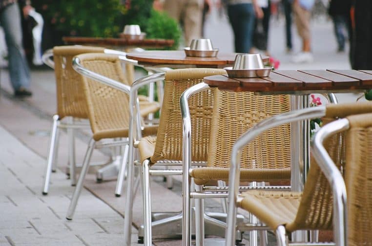 Terrasse de café à Turku, avec des tables alignées et des chaises en osier sur le trottoir.
