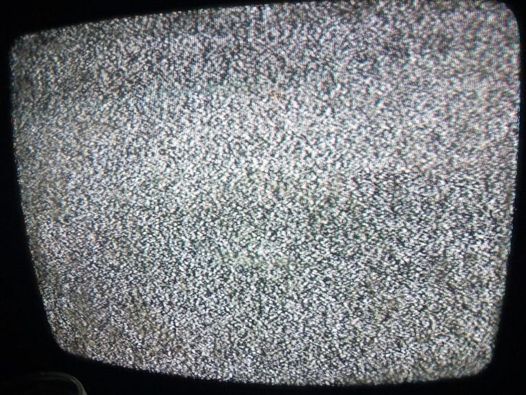 Écran de télévision affichant de la neige et du brouillage, ambiance de panne de signal, prise de vue rapprochée.
