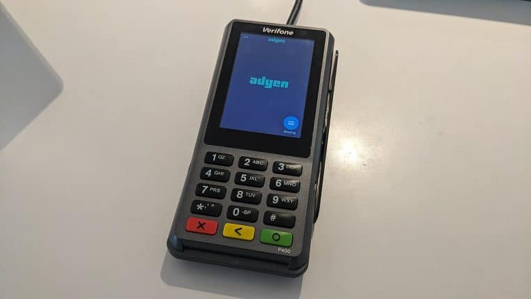 Terminal de paiement bancaire posé sur un comptoir, clavier et écran visibles, gros plan en intérieur, vue inclinée.