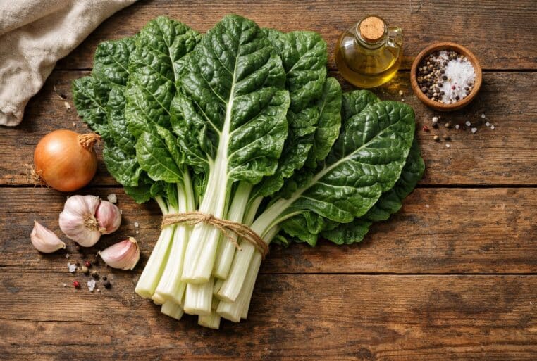 Blette fraîche en botte sur table en bois avec ail, oignon et huile d’olive