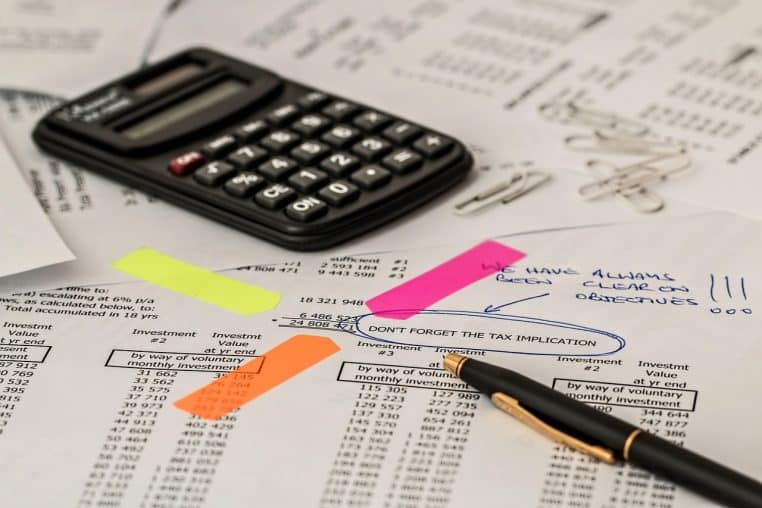 Calculatrice posée sur des documents, évoquant le calcul de l’impôt et des retenues sur salaire.