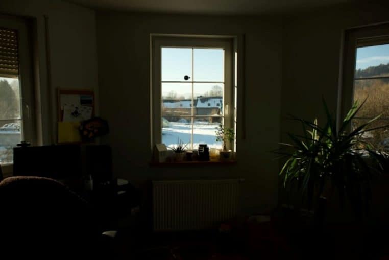 Rayons de soleil traversant une fenêtre, paysage enneigé à l’extérieur.