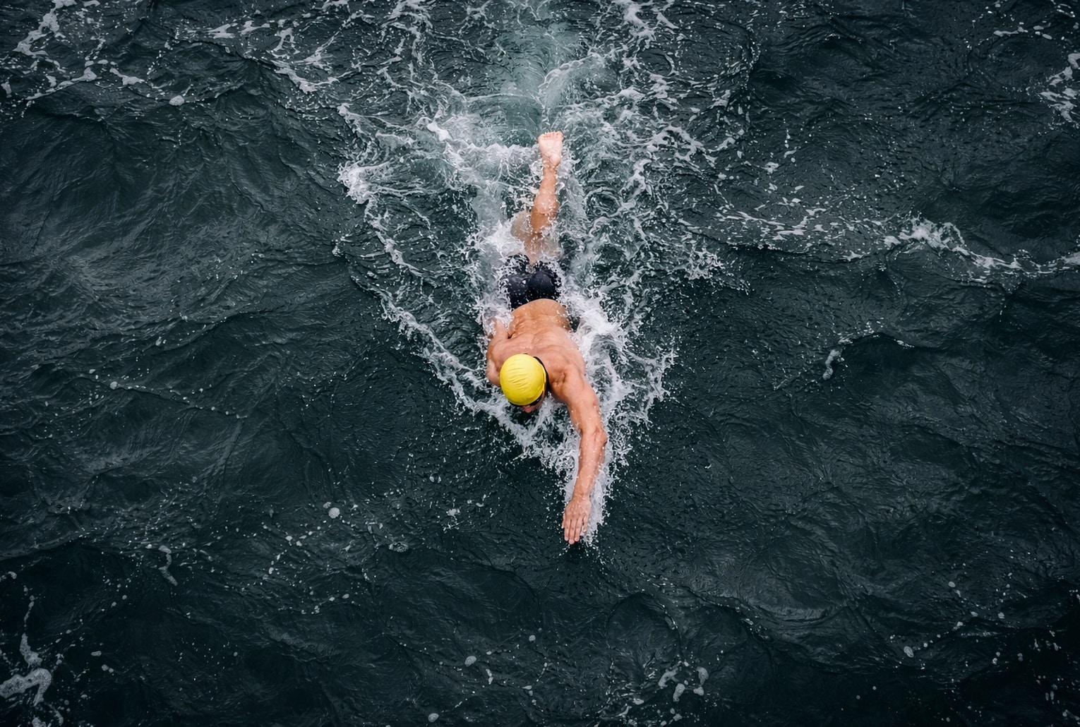 Nageur en eau libre vu du ciel, nageant seul dans l’océan