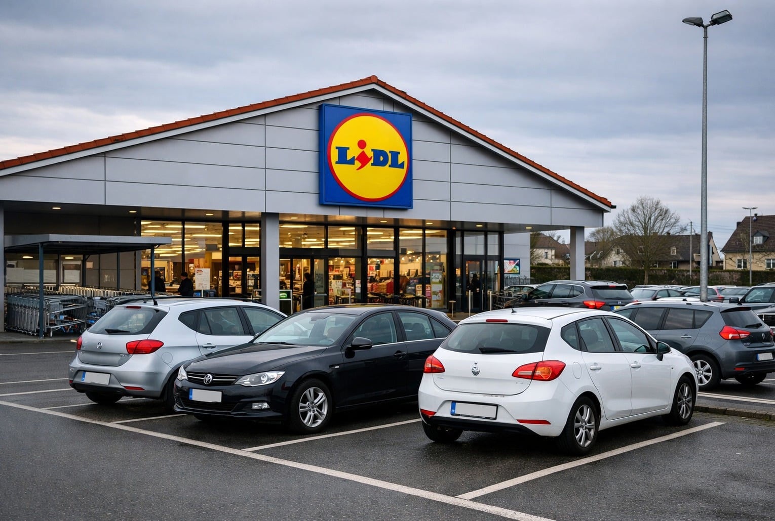 Parking devant un Lidl, avec plusieurs voitures stationnées face à l’entrée et le logo de l’enseigne au centre de la façade.