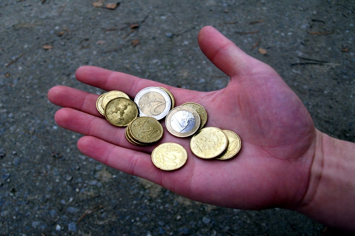 Main tenant plusieurs pièces en euros, gros plan sur la monnaie.