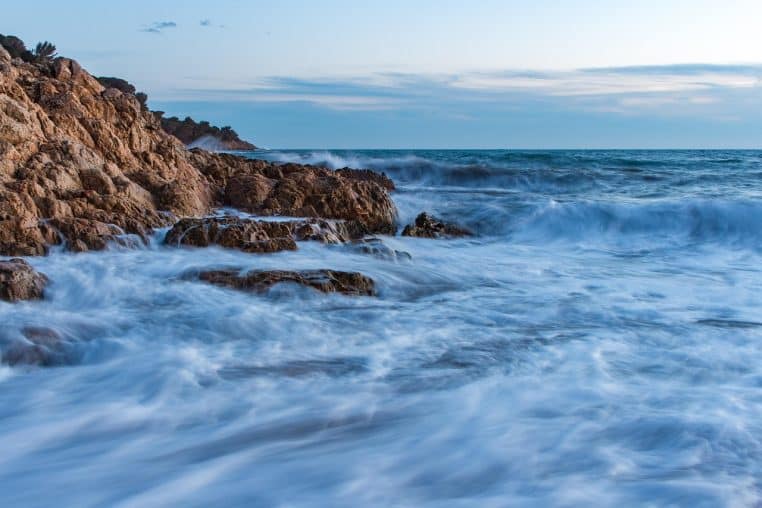 Mer agitée et vagues frappant des rochers sous un ciel chargé, ambiance de coup de vent sur la côte