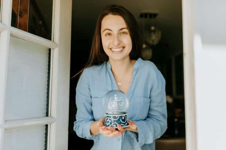 A happy woman poses with a decorative Hanukkah snow globe, capturing the festive spirit.