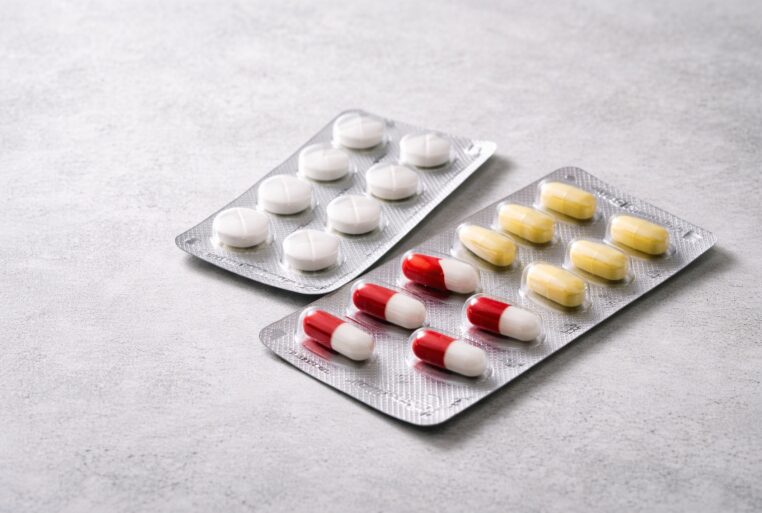 Trois plaquettes de médicaments sur fond neutre, illustration sobre des médicaments du quotidien.