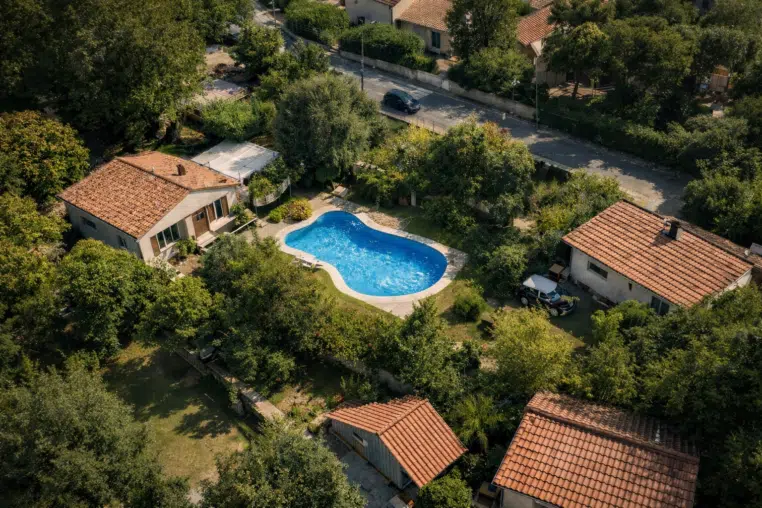 Vue aérienne d’un quartier résidentiel : une piscine bien visible dans un jardin.