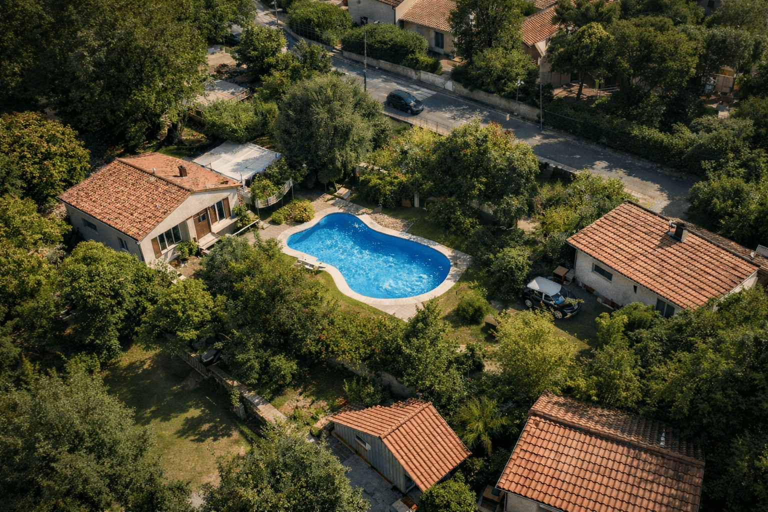 Vue aérienne d’un quartier résidentiel : une piscine bien visible dans un jardin.