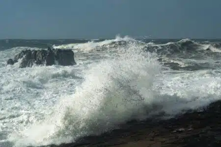 Crashing ocean waves against rocky shore under a stormy sky