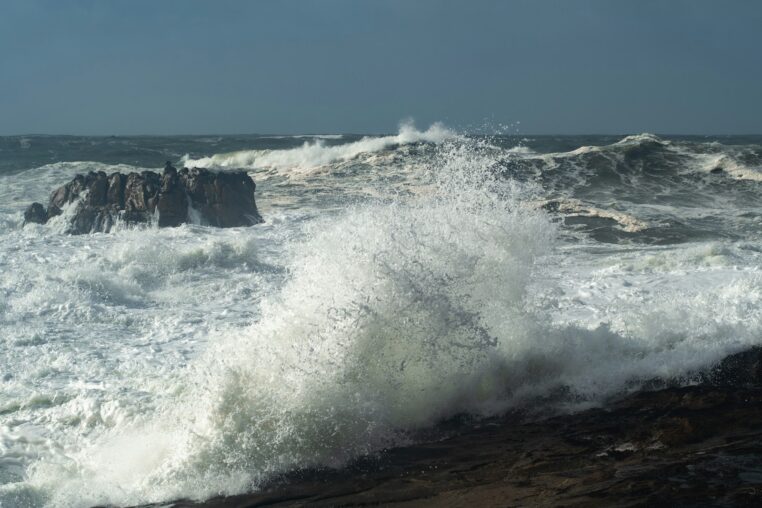 Crashing ocean waves against rocky shore under a stormy sky