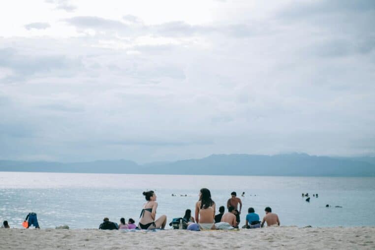 A serene beach scene with people enjoying the sun, sand, and sea.
