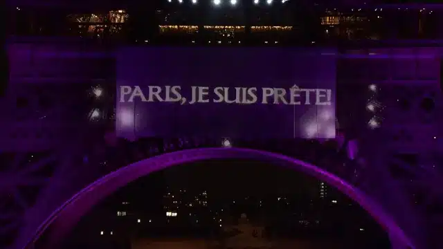 La Tour Eiffel est illuminée en violet avec une bannière affichant "PARIS, JE SUIS PRÊTE!".