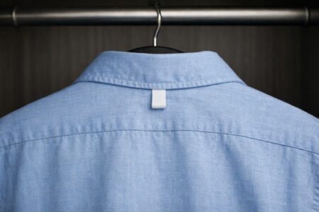 Boucle au dos de la chemise visible dans une penderie.