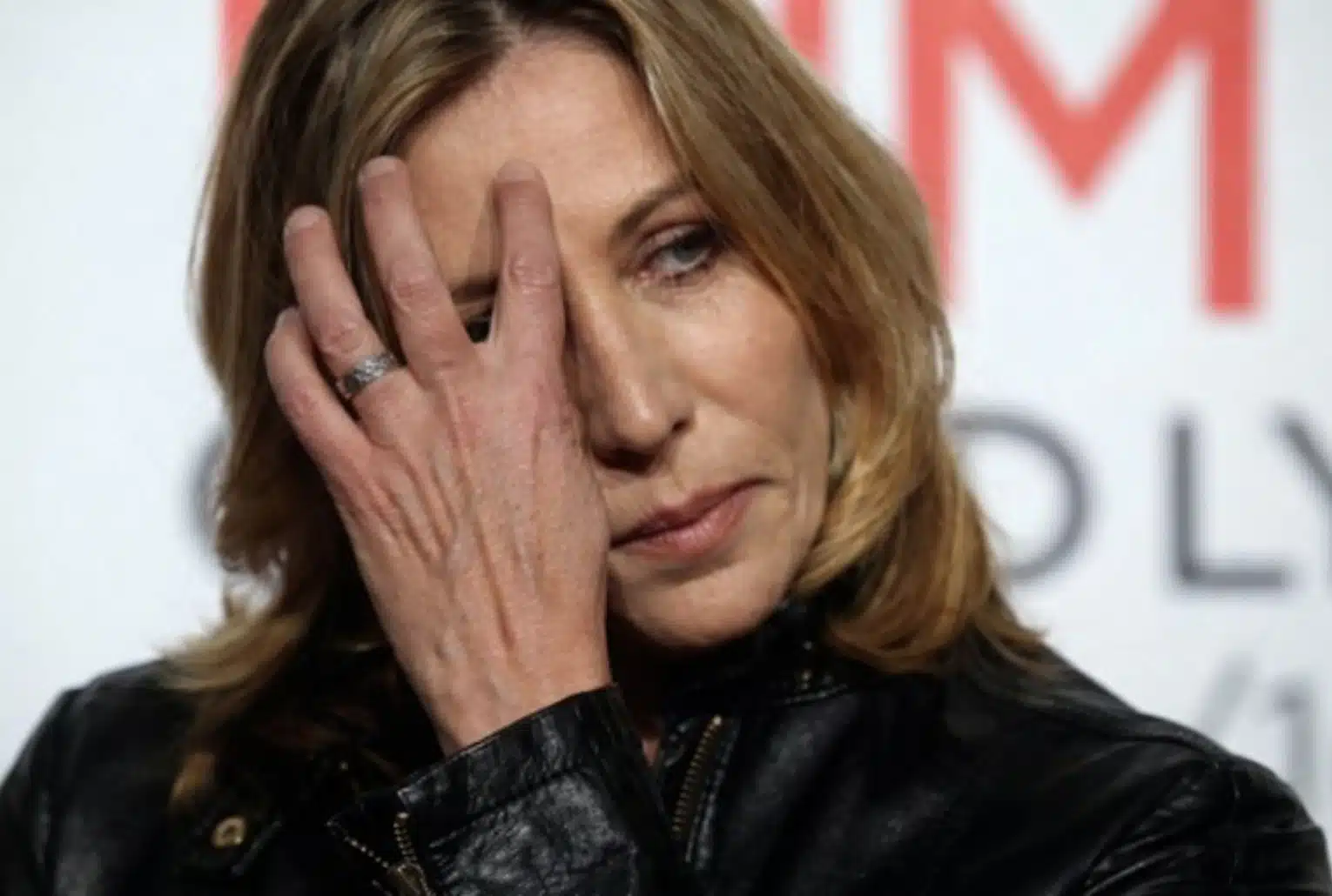 Mathilde Seigner en gros plan, la main devant le visage, avec une expression grave