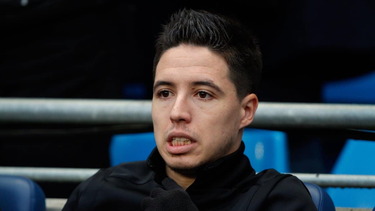 Samir Nasri assis en tribune, regard pensif, veste noire