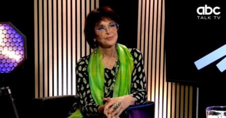 Anny Duperey en interview sur le plateau d'ABC Talk TV, portant une veste noire à motifs et un foulard vert