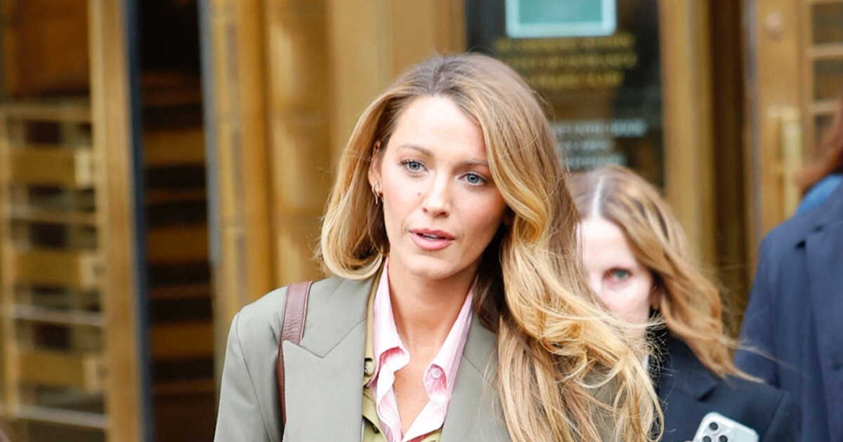 Blake Lively sortant d'un tribunal, cheveux blonds ondulés, veste kaki et chemise rose