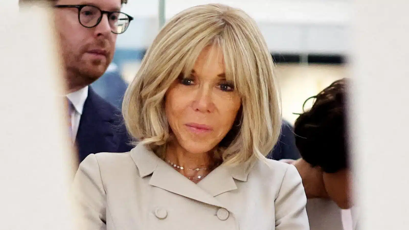Brigitte Macron en manteau beige, regard discret, gros plan visage