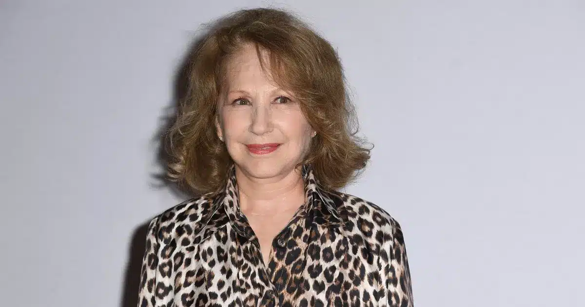 Nathalie Baye en chemise léopard, portrait souriant sur fond clair