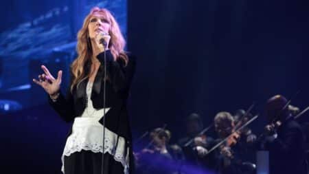 Céline Dion sur scène lors d'un concert, micro en main, devant un orchestre