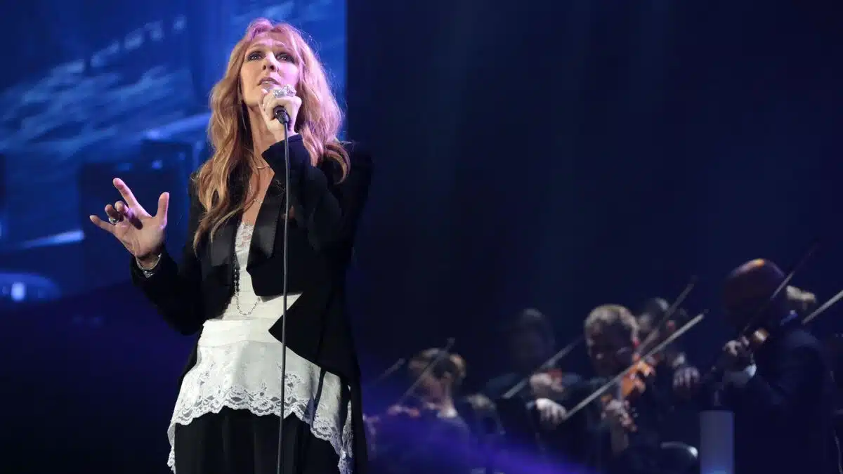 Céline Dion sur scène lors d'un concert, micro en main, devant un orchestre