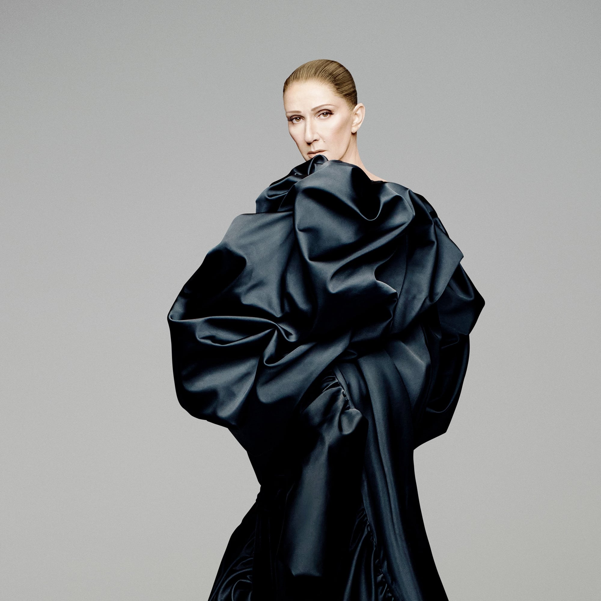 Céline Dion en robe noire volumineuse, regard intense, pose artistique