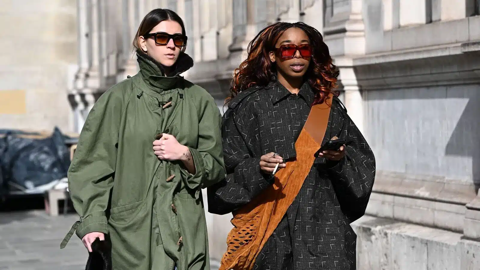 Deux femmes aux lunettes de soleil tendance marchant dans les rues de Paris lors de la Fashion Week, illustrant le style des Gémeaux et Vierge