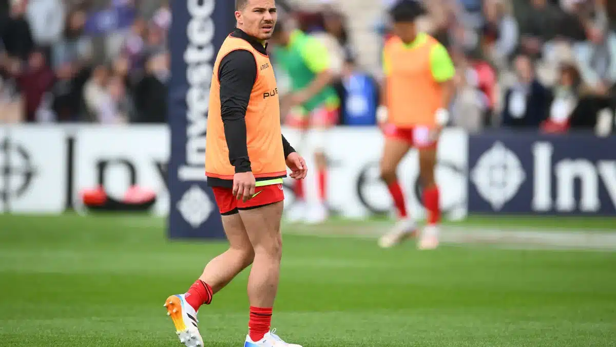 Antoine Dupont à l'échauffement avant le match de Champions Cup, portant un chasuble orange sur le maillot rouge de Toulouse