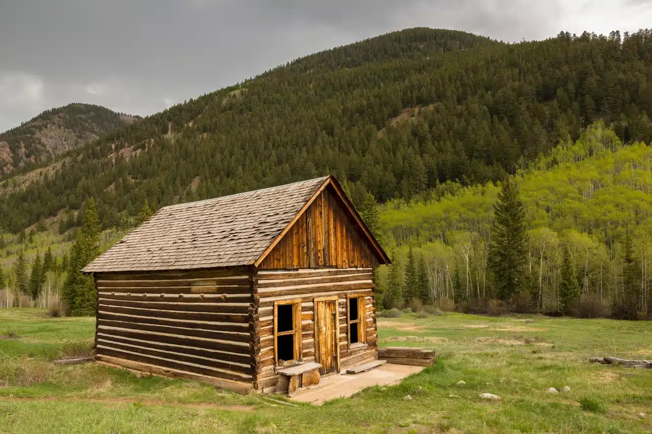 Cabane en bois rustique dans une vallée forestière de montagne, entourée d'arbres verts
