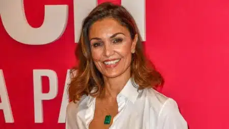 Nadia Farès souriante en chemise blanche lors d'un événement, portrait chaleureux de l'actrice