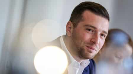 Jordan Bardella en gros plan, souriant légèrement, regard vers le haut