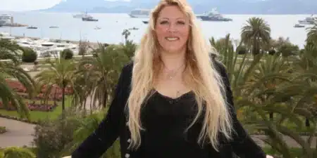 Loana souriante à Cannes, en tenue noire, avec la mer et les palmiers en arrière-plan