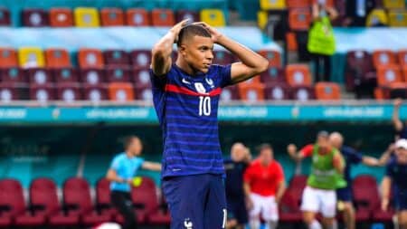 Kylian Mbappé, joueur de football, se tient la tête sur